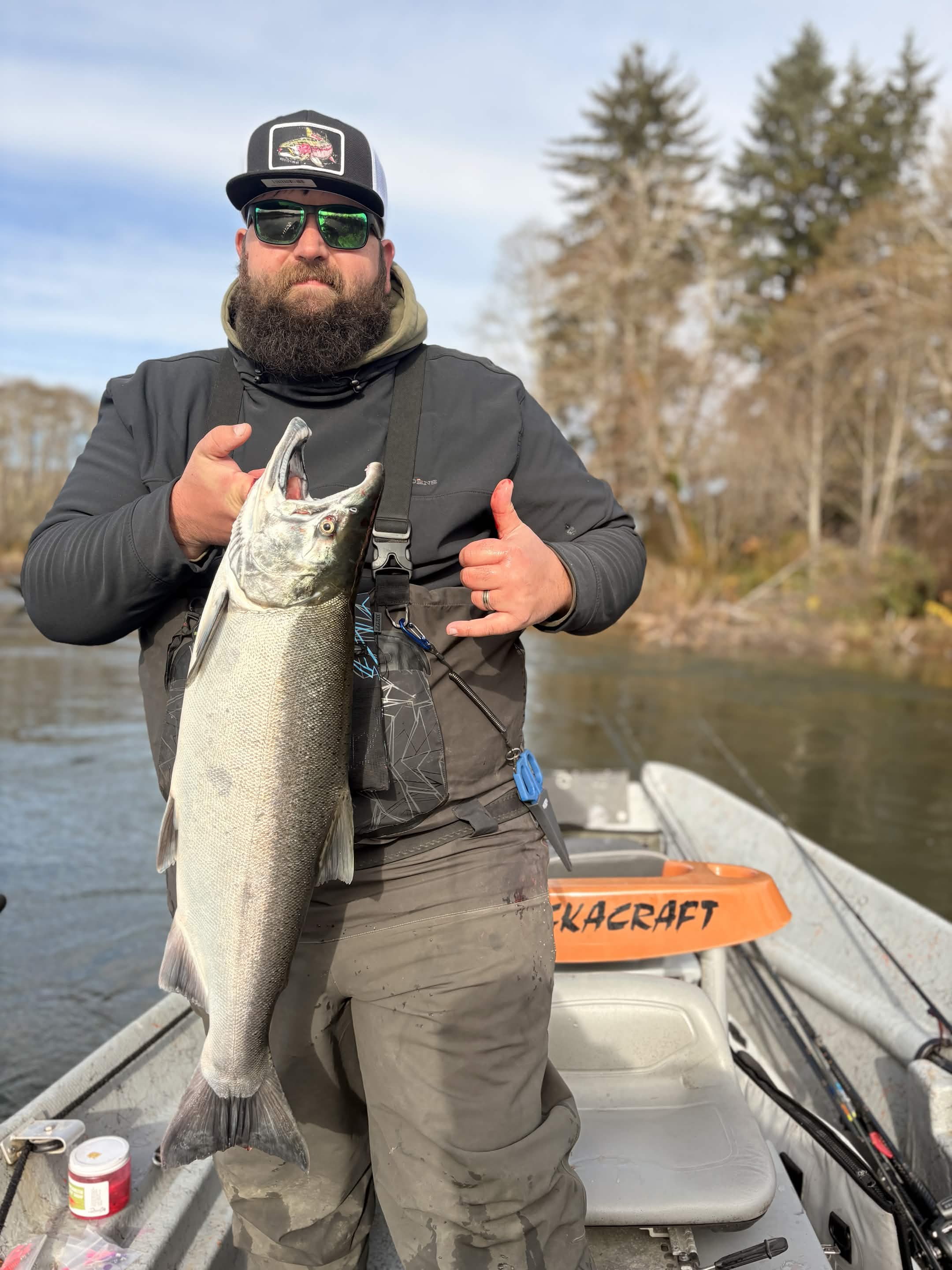 Smiling angler holding a coho salmon on the river