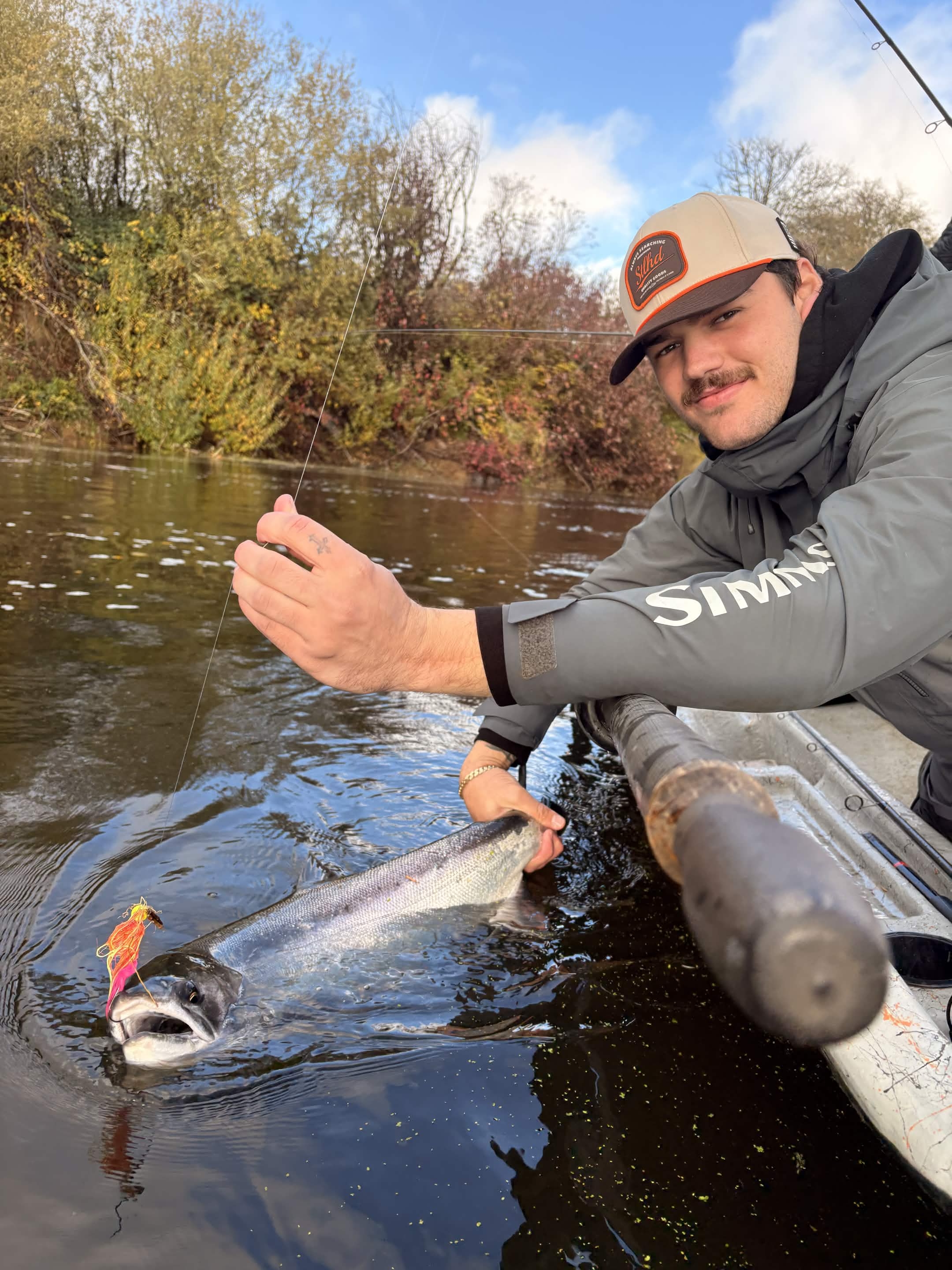 Angler with a winter steelhead on a misty Washington river